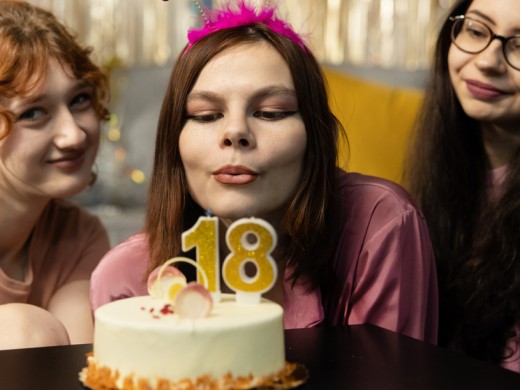 Portrait of girl looking at birthday cake surrounded by friends at party.